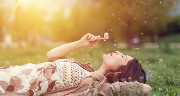 Relaxed woman in the park blowing dandelion